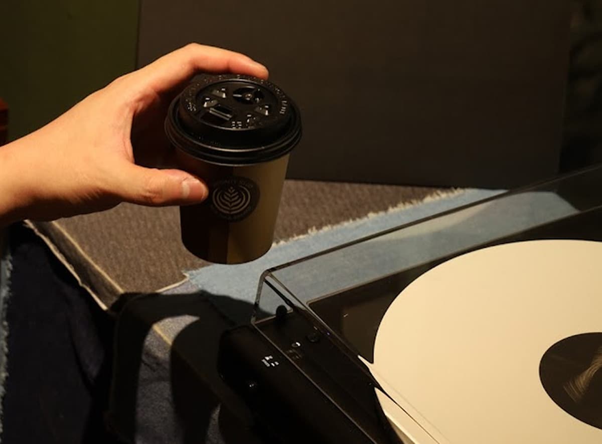 Hand holding a cup near a record player